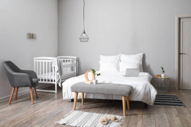 Beyaz karyolası ve koltuğu olan aydınlık yatak odasının içi