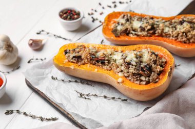 Beyaz ahşap arka planda içi doldurulmuş balkabaklarıyla dolu bir tahta.