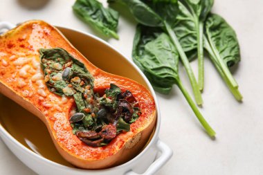 Hafif arka planda içi doldurulmuş balkabağı dolu fırın tabağı, yakın plan.