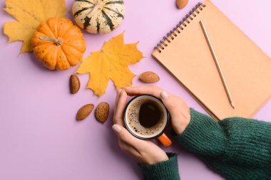 Bir fincan kahveli kadın elleri, olgun balkabakları ve renkli fındıklı badem fıstıkları, yakın plan.