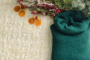 Sıcak süveter, kurutulmuş portakal dilimleri ve hafif kumaş arka planda köknar dalları, yakın plan.