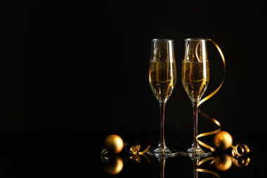 Şampanya kadehleri ve karanlık arka planda Noel süslemeleri.