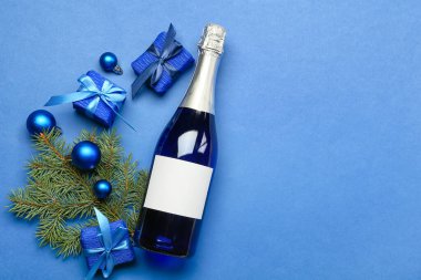 Bir şişe şampanya ve mavi arka planda Noel dekoru.