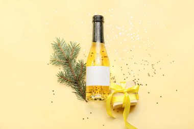 Köknar dallı bir şişe şampanya ve renkli bir hediye.