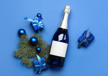 Bir şişe şampanya ve mavi arka planda Noel dekoru.