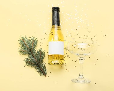 Köknar dallı bir şişe şampanya ve arka planda konfeti.