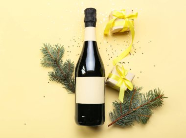 Köknar dallı bir şişe şampanya ve renkli arka planda hediyeler.