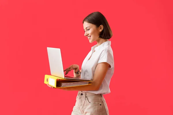 Schöne Junge Frau Mit Ordner Und Laptop Auf Farbigem Hintergrund — Stockfoto