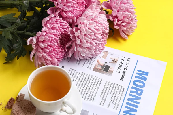 Schöne Chrysanthemenblüten Zeitung Und Tasse Tee Auf Gelbem Hintergrund Nahaufnahme — Stockfoto