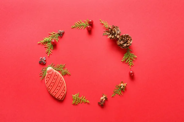 由冷杉树枝 圆锥和红底圣诞饼干制成 — 图库照片