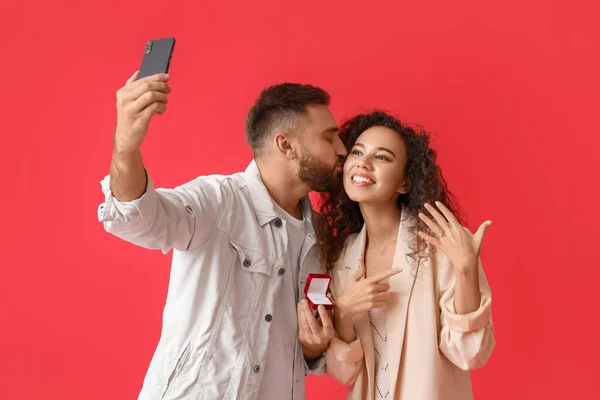 Pareja Joven Comprometida Tomando Selfie Sobre Fondo Color — Foto de Stock