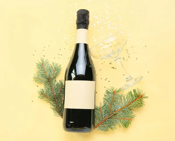 Köknar dallı bir şişe şampanya ve renkli arka planda konfeti.