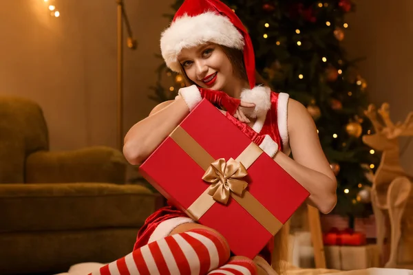 穿着圣诞老人服装 家里还带着圣诞礼物的性感年轻女人 — 图库照片