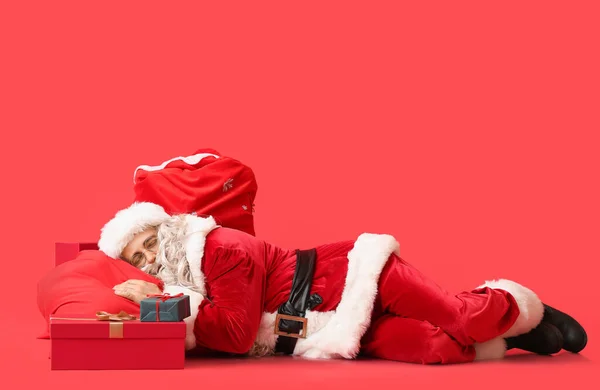 Kerstman Met Tassen Cadeautjes Slapen Rode Achtergrond — Stockfoto