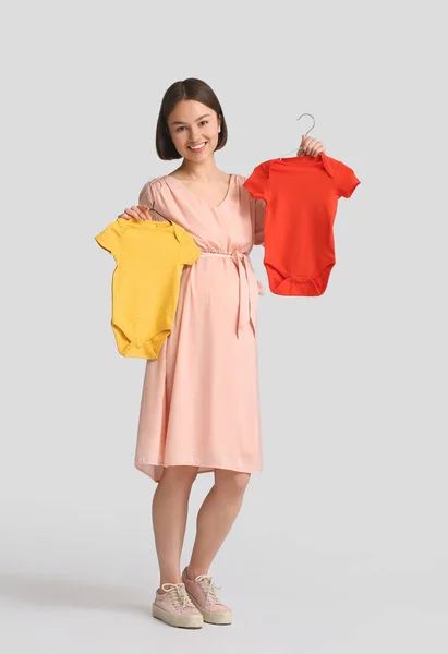Jonge Zwangere Vrouw Met Baby Bodysuits Lichte Achtergrond — Stockfoto
