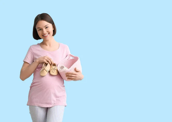 Young Pregnant Woman Holding Basket Baby Shoes Blue Background — Stock Photo, Image