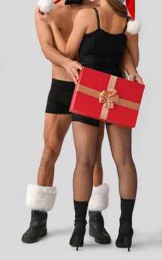 İç çamaşırlı seksi genç bir çift ve hafif arka planda bir Noel hediyesi.