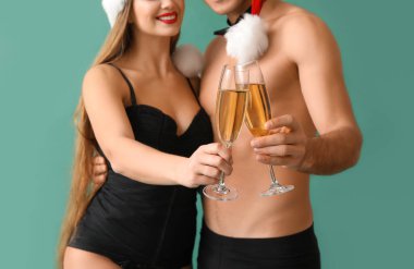 İç çamaşırlı, Noel Baba şapkalı ve şampanyalı seksi genç çift.