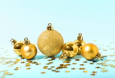 Mavi arka planda altın Noel topları ve konfeti