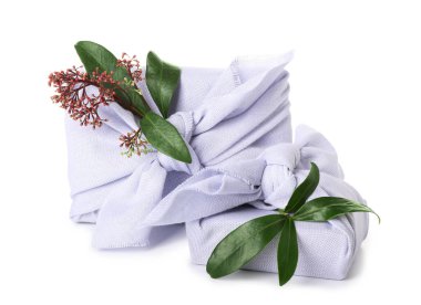 Beyaz arkaplanda bitki dalları olan kumaşa sarılı hediyeler