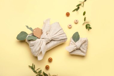 Kumaşa sarılı hediye kutuları, ahşap boncuklar ve arkaplanda çiçek dekoru