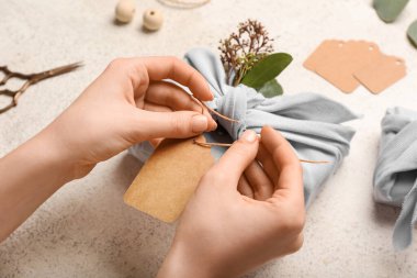 Işıklı arka planda kumaşa sarılı kadın hediye kutusu, yakın plan.