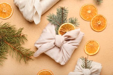 Kumaşa sarılı Noel hediyeleri, köknar dalları ve arka planda kurutulmuş portakal dilimleri ile kompozisyon, yakın plan