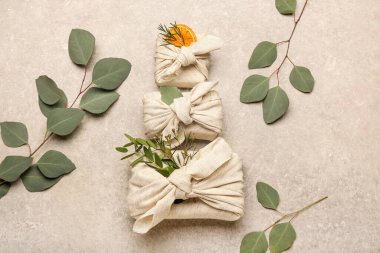 Kumaş ve okaliptüs dallarına sarılı farklı hediye kutuları.