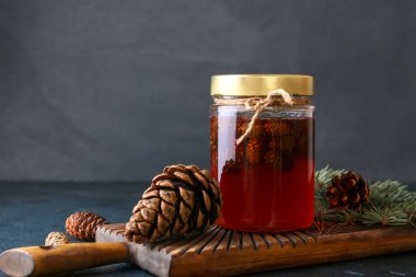 Koyu arkaplanda bir kavanoz lezzetli kozalak reçeli olan tahta, yakın plan.