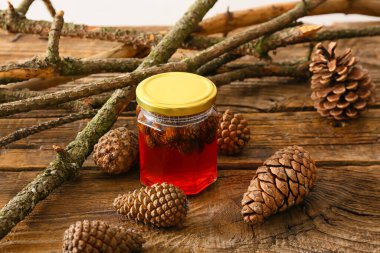 Lezzetli bir kavanoz kozalak reçeli ve ağaç dalları ahşap masada.