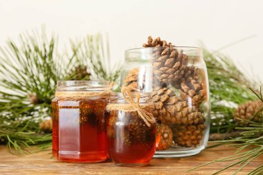 Lezzetli kozalak reçeli kavanozları ve ahşap masada köknar ağacı dalları.