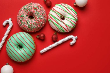 Kırmızı arka planda topları ve bastonları olan lezzetli Noel çörekleri.