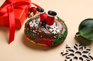 Lezzetli bir Noel çöreği, kar tanesi figürü, toplar ve bej arka planda hediye, yakın plan.