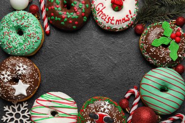 Köknar ağacı dallı lezzetli Noel çöreklerinden yapılmış çerçeve, koyu arkaplanda toplar ve şeker kamışları