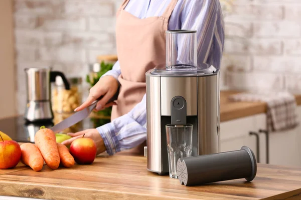Kadın mutfaktaki masada taze meyve suyu yapıyor.
