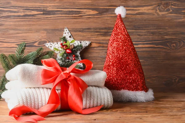 木製の背景にリボンとクリスマスの装飾で結ばれたニットセーターのスタック — ストック写真