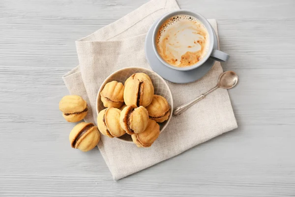 Bir kase lezzetli ceviz şeklindeki kurabiyeler. Yoğunlaştırılmış süt ve bir fincan kahve.