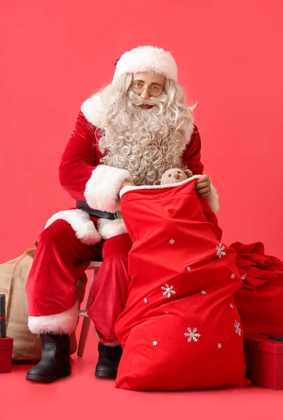 Kerstman Met Tas Cadeautjes Rode Achtergrond — Stockfoto