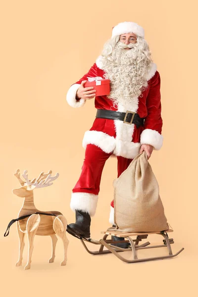 Święty Mikołaj Prezentem Workiem Saniami Drewnianym Reniferem Beżowym Tle — Zdjęcie stockowe