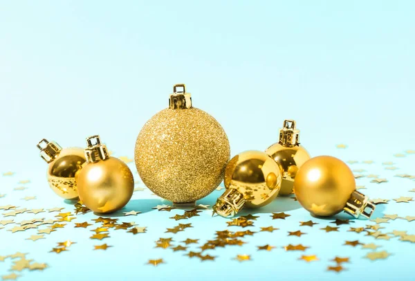 Mavi arka planda altın Noel topları ve konfeti