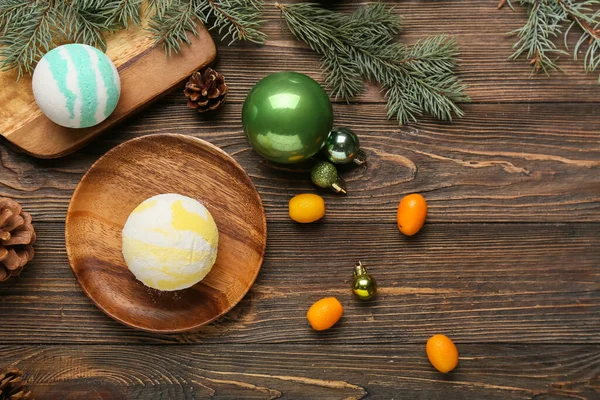 Banyo bombası, kumkat meyveleri, Noel topları ve ahşap arka planda köknar dalları olan kompozisyon