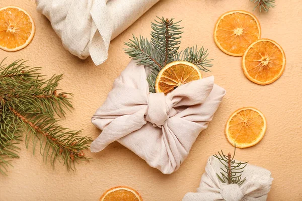 Kumaşa sarılı Noel hediyeleri, köknar dalları ve arka planda kurutulmuş portakal dilimleri ile kompozisyon, yakın plan