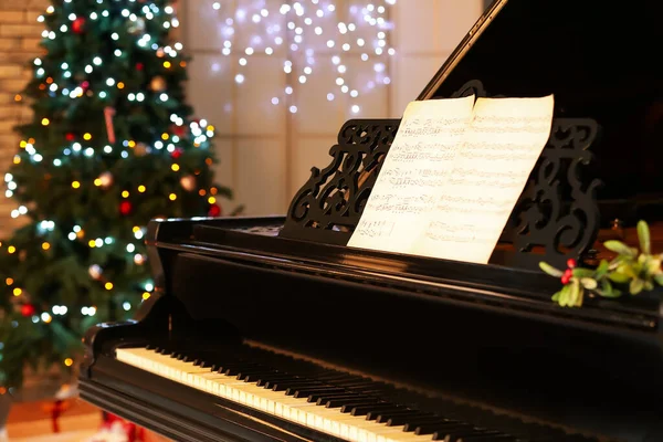 クリスマスのために装飾された部屋にノートシート付きブラックグランドピアノ クローズアップ — ストック写真