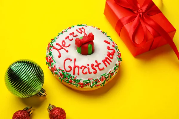 Leckere Weihnachts Donut Mit Kugeln Und Geschenk Auf Gelbem Hintergrund — Stockfoto