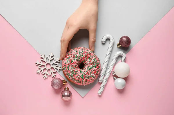 Weibliche Hand Mit Leckerem Weihnachts Donut Und Dekor Auf Rosa — Stockfoto