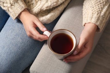 Evdeki kanepede çay içen kadın.