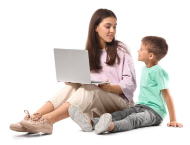 Küçük çocuk ve ablası beyaz arka planda dizüstü bilgisayar kullanıyorlar.