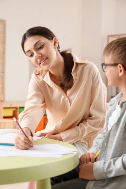 Küçük çocuk evde ablasıyla resim çiziyor.