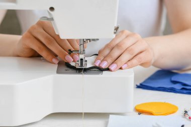 Dikiş makinesi olan kadın tekrar kullanılabilir pamuk yastığı yapıyor, yakın plan.