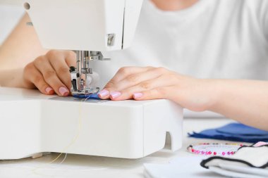 Dikiş makinesi olan kadın tekrar kullanılabilir pamuk yastığı yapıyor, yakın plan.